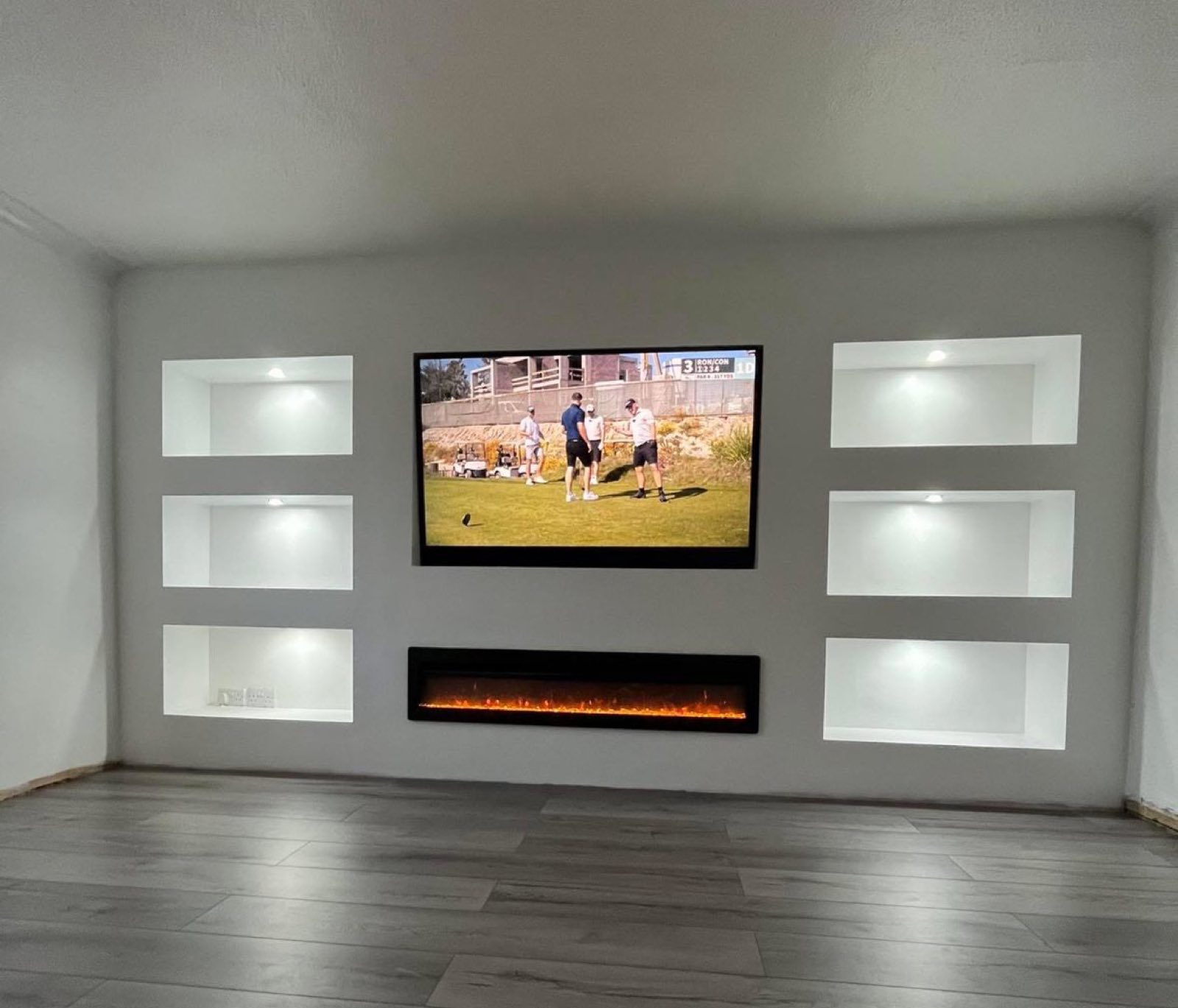 Media wall with lit alcoves and electric fire