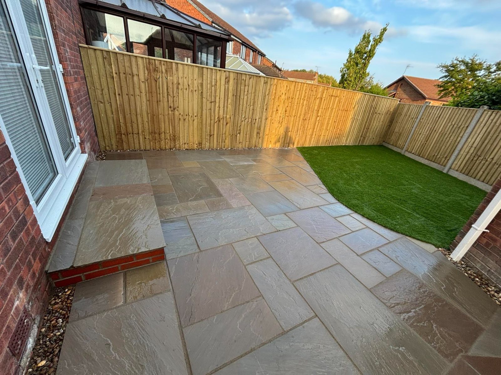 Indian sandstone patio with fencing and turf